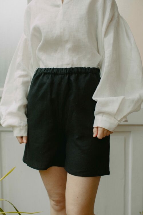 Leinenshorts in Schwarz aus 100 % niederländischem Leinen, mit Gummibund, seitlichen Eingriffstaschen und leicht ausgestelltem Bein.