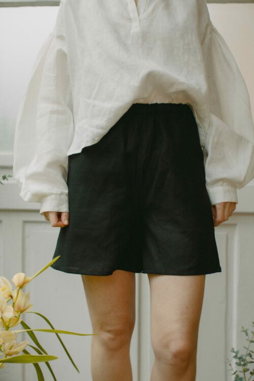 Leinenshorts in Schwarz aus 100 % niederländischem Leinen, mit Gummibund, seitlichen Eingriffstaschen und leicht ausgestelltem Bein.